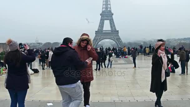 PARÍS, FRANCIA - 31 DE DICIEMBRE DE 2016. Turistas multinatonales masculinos y femeninos haciendo fotos cerca de la Torre Eiffel en un día de niebla. El destino turístico y turístico francés más popular. Vídeo 4K — Vídeos de Stock