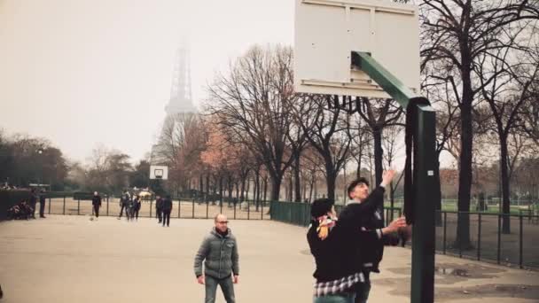 PARIS, FRANÇA - DEZEMBRO, 31 de dezembro de 2016. Adolescentes multinatonais jogando basquete de rua contra a Torre Eiffel em um dia nebuloso. Vídeo 4K — Vídeo de Stock