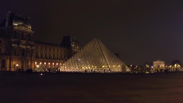 ПАРИЖ, ФРАНЦИЯ - 31 ДЕКАБРЯ 2016 года. Стеадикам снимал силуэты туристов возле стеклянных пирамид ночью. Известный французский музей и популярное туристическое направление. 4K клип — стоковое видео