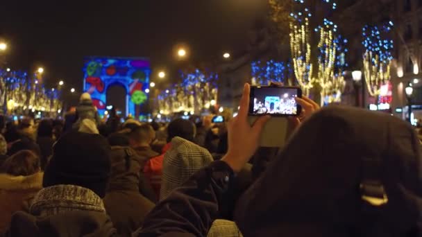 Turistas irreconhecíveis gravando vídeos e tirando fotos do show de luz de Ano Novo perto do famoso arco triunfal, Arco do Triunfo, em Paris. Vídeo 4K — Vídeo de Stock