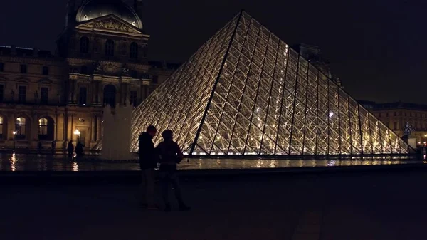 Paris, Frankreich - Dezember 31, 2016. Touristen Silhouetten in der Nähe von Glaslamellenpyramide in der Nacht. berühmtes französisches Museum und beliebtes Touristenziel — Stockfoto
