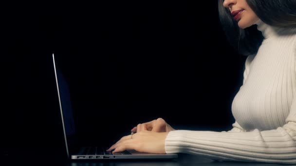 Beautiful brunette woman working on her laptop against black background. 4K video — Stock Video