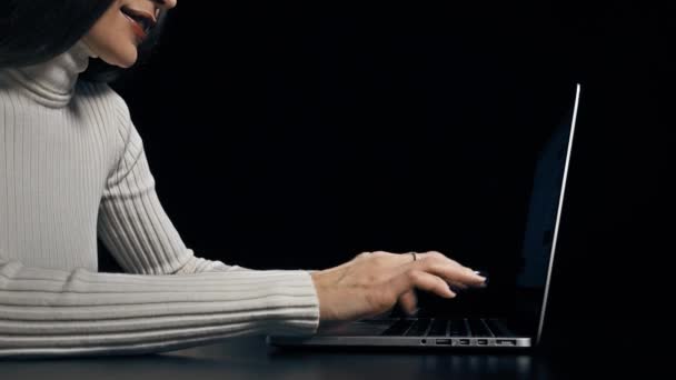 Young brunette woman typing on her laptop against black background. 4K video — Stock Video