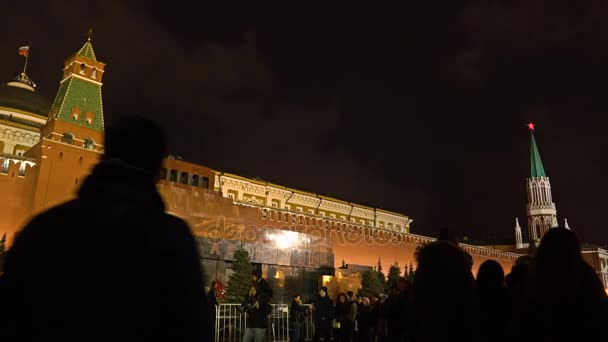 MOSCOW, RÚSSIA - JANEIRO, 2, 2017. Os turistas caminham contra a parede iluminada do Kremlin e o mausoléu Lenins na Praça Vermelha à noite. 4K tiro de ângulo baixo — Vídeo de Stock