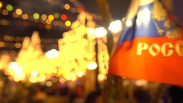 Ondeando la bandera rusa de cerca y desenfocando a la gente en el tradicional mercado de Año Nuevo en la Plaza Roja, Moscú. Vídeo 4K — Vídeo de stock