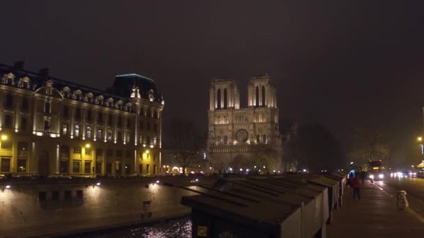 Fachada occidental de la famosa catedral de Notre Dame de París iluminada por la noche. Destino turístico popular en Francia. Vídeo 4K — Vídeo de stock