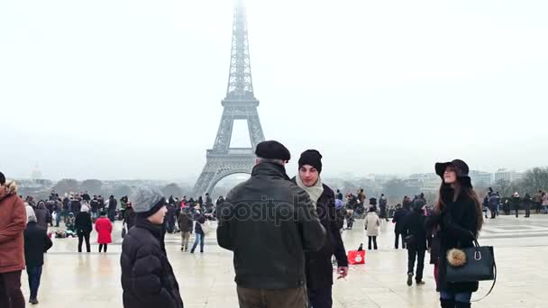 ปารีส, ฝรั่งเศส - 31 ธันวาคม 2016 คู่รักหนุ่มสาว โพสอยู่ใกล้หอไอเฟล ในวันที่มีหมอก สถานที่ท่องเที่ยวและสถานที่ท่องเที่ยวที่นิยมมากที่สุดของฝรั่งเศส 4K วิดีโอ — วีดีโอสต็อก