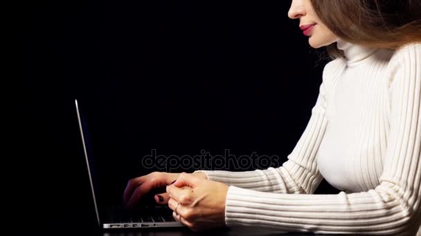 美しいブルネットの女性は、ラップトップを使用して彼女のクレジット カードでオンライン決済を行います。黒背景、温かみのある色調、碑文やインフォ グラフィックのためのスペース。E コマースのコンセプトです。4 k ビデオ — ストック動画