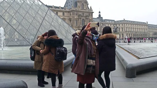 Paris, Frankrike -, 31 December 2016. Kvinnliga asiatiska turister poserar och göra bilder nära Louvren, berömda franska museet populära turistdestinationen — Stockfoto