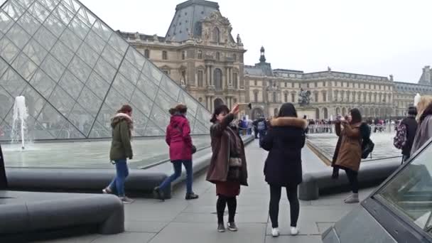 PARIS, FRANÇA - DEZEMBRO, 31 de dezembro de 2016. Turistas asiáticos posando e fazendo fotos perto do Louvre, famoso museu francês e destino turístico popular. 4K steadicam vídeo — Vídeo de Stock