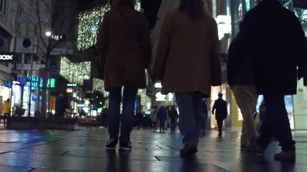 Vienna, Oostenrijk - December, 24, 2016 Steadicam schot van toeristen in verlichte straat wandelen in de avond. Populaire bestemming met winkels en cafés. 4k video — Stockvideo