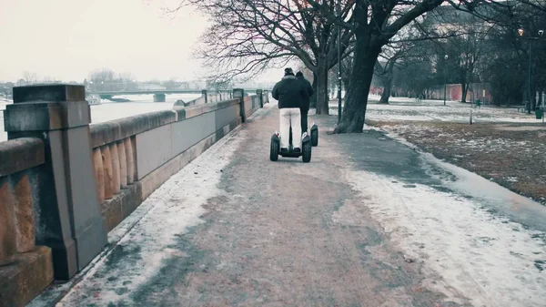 Dois homens irreconhecíveis viajando em segways ao longo do dique do rio no inverno — Fotografia de Stock