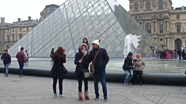 PARÍS, FRANCIA - 31 DE DICIEMBRE DE 2016. Parejas haciendo selfies cerca del Louvre, famoso museo francés y popular destino turístico — Foto de Stock