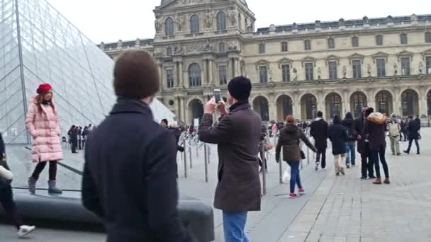 PARIS, FRANCE - DECEMBER, 31, 2016. Couples making photos and selfies near the Louvre pyramid. 4K clip — Stock Video