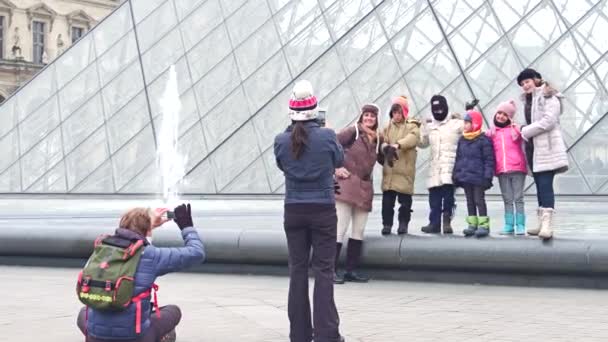 Paris, Frankrijk - 31 December 2016. Vrolijke familie poseren en het maken van foto's in de buurt van het Louvre, de beroemde Franse museum en de populaire toeristische bestemming. 4k video — Stockvideo