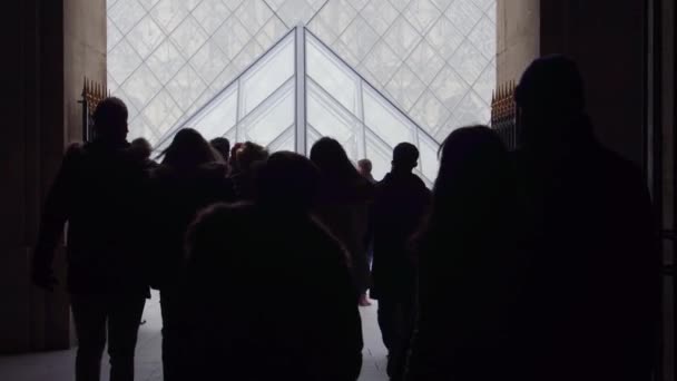 PARÍS, FRANCIA - 31 DE DICIEMBRE DE 2016. Steadicam fotografió siluetas de turistas caminando cerca de la pirámide de vidrio del Louvre. Popular museo francés y destino turístico. Vídeo 4K — Vídeos de Stock