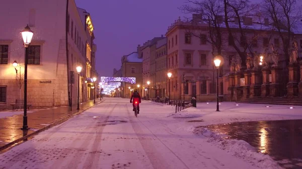 Улица старого города и одинокий байкер, катающийся по снегу — стоковое фото