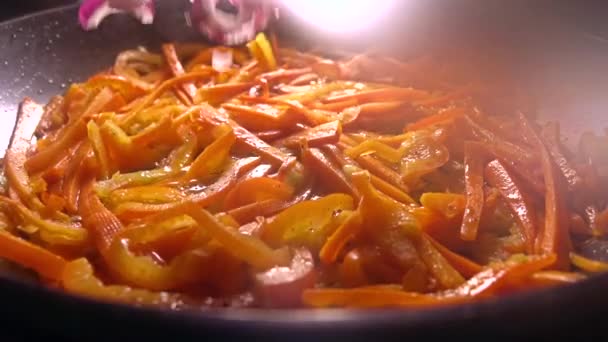 Het toevoegen van rode ui paprika stukken in een koekenpan. Thuis koken. Slow motion close-up video — Stockvideo