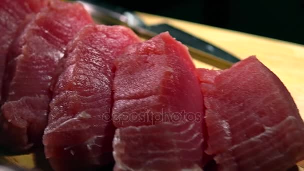 Corte pedaços de filé de atum em tábua de madeira. 4K close-up dolly vídeo — Vídeo de Stock