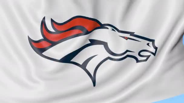 Primo piano della bandiera sventolante con il logo della squadra di football americano Denver Broncos NFL, anello senza cuciture, sfondo blu. Animazione editoriale. 4K — Video Stock