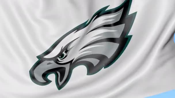 Крупный план размахивания флагом с логотипом футбольной команды NFL Philadelphia Eagles, бесшовный цикл, синий фон. Редакционная анимация. 4K — стоковое видео
