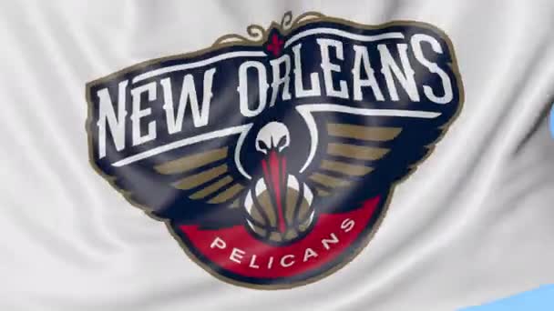 Gros plan du drapeau ondulé avec le logo de l'équipe de basket-ball de la Nouvelle-Orléans Pelicans NBA, boucle transparente, fond bleu. Animation éditoriale. 4K — Video