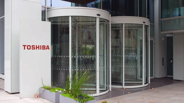 Straat signalisatie bord met Toshiba Corporation logo. Modern kantoorgebouw. Redactioneel 3D-rendering — Stockfoto