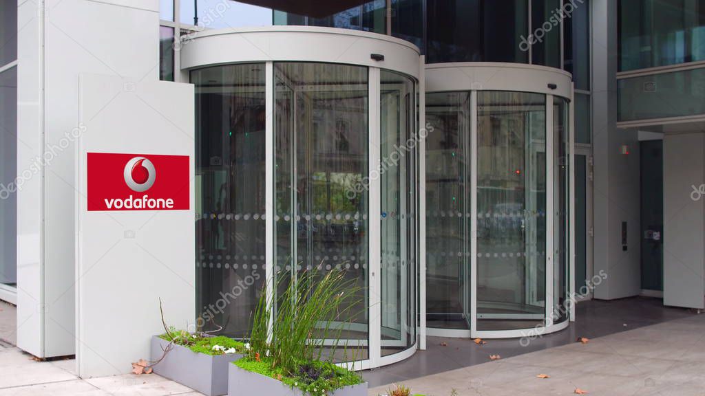 Street signage board with Vodafone logo. Modern office building. Editorial 3D United States