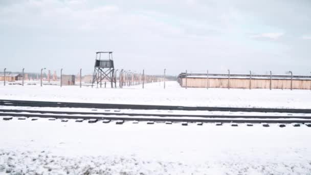 Steadicam colpo di recinzione del campo di concentramento, torre di guardia e binari ferroviari in inverno. Video 4K — Video Stock