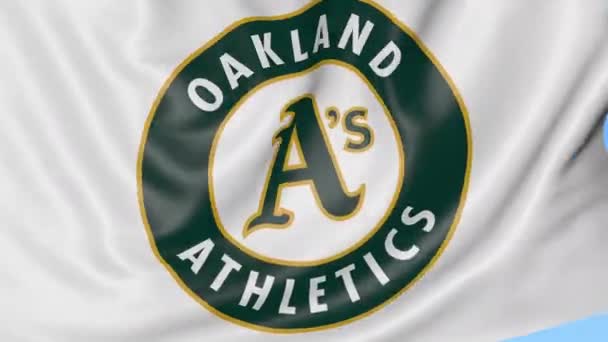 Gros plan du drapeau ondulé avec le logo de l'équipe de baseball Oakland Athletics MLB, boucle transparente, fond bleu. Animation éditoriale. 4K — Video