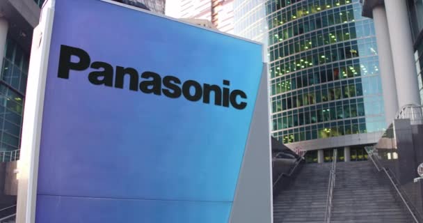 Et gateskilt med Panasonic Corporation-logo. Moderne kontorskyskraper og trappebakgrunn. Redaksjonell 3D-gjengivelse 4K – stockvideo
