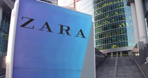 Cartelera con el logotipo de Zara. Rascacielos moderno centro de oficina y escaleras de fondo. Editorial 3D renderizado 4K — Vídeos de Stock