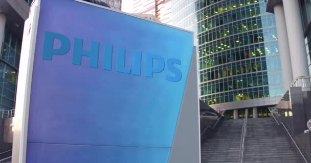 Уличная вывеска с логотипом Philips. Современный офисный центр небоскреб и лестница фон. 3D-рендеринг в 4K — стоковое видео
