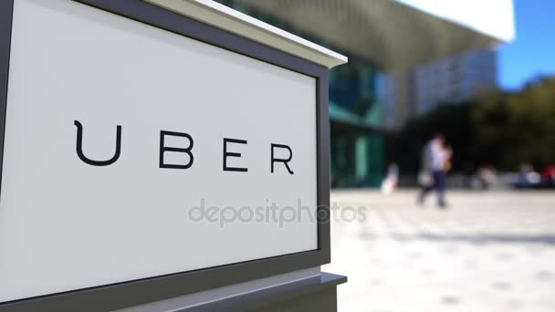 Tablero de señalización con logotipo de Uber Technologies Inc.. Centro de oficina borrosa y gente caminando fondo. Editorial 3D renderizado 4K — Vídeo de stock