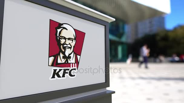 Straat signalisatie bord met Kentucky Fried Chicken Kfc logo. Wazig office center en wandelende mensen achtergrond. Redactionele 3d rendering van 4k — Stockvideo