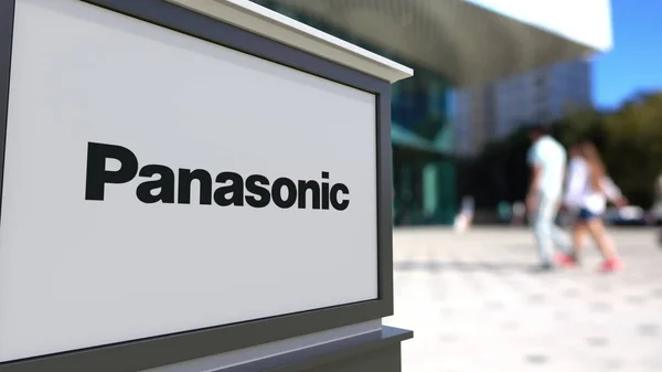Tablero de señalización con el logotipo de Panasonic Corporation. Centro de oficina borrosa y gente caminando fondo. Representación Editorial 3D —  Fotos de Stock