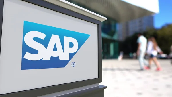 Tablero de señalización con logotipo de SAP SE. Centro de oficina borrosa y gente caminando fondo. Representación Editorial 3D —  Fotos de Stock