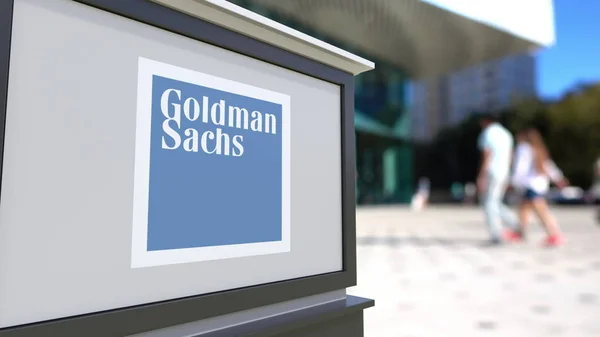 Straat signalisatie bord met het logo van Goldman Sachs Group, Inc. Wazig office center en wandelende mensen achtergrond. Redactioneel 3D-rendering — Stockfoto