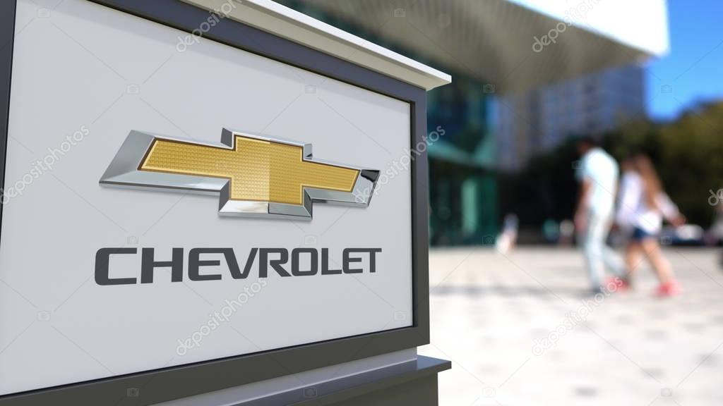 Street signage board with Chevrolet logo. Blurred office center and walking people background. Editorial 3D United States