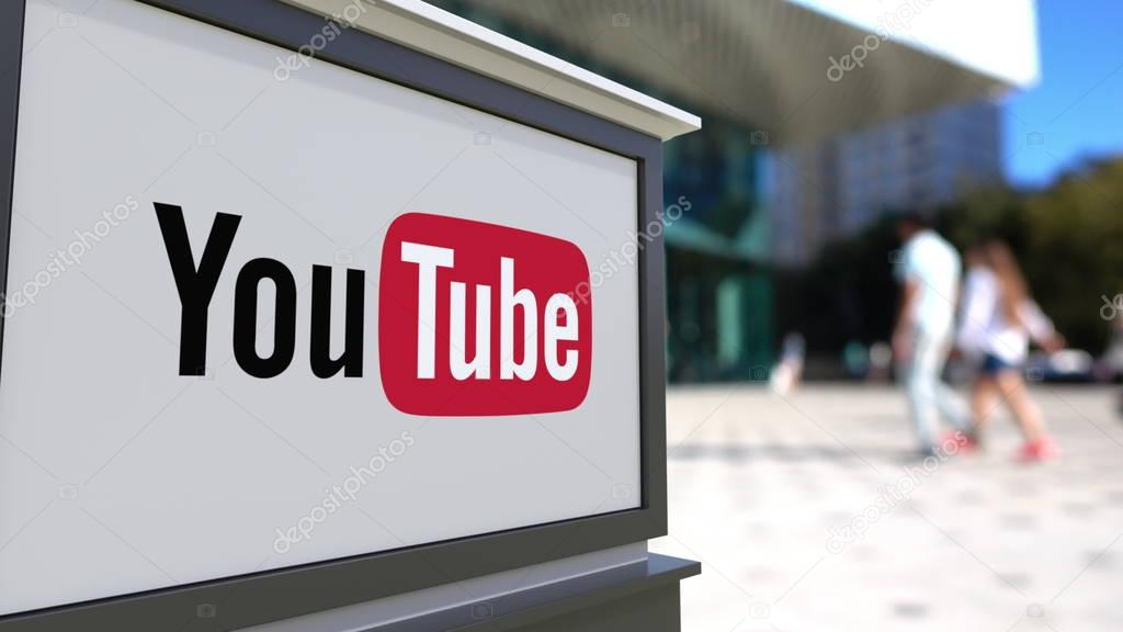Street signage board with YouTube logo. Blurred office center and walking people background. Editorial 3D United States