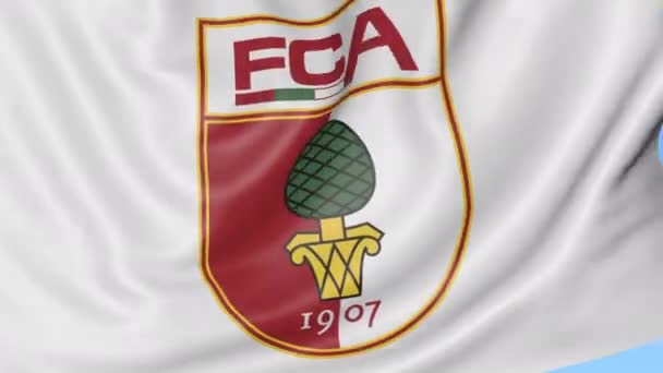 Nahaufnahme einer schwenkenden Fahne mit dem Logo des FC Augsburg, nahtlose Schlaufe, blauer Hintergrund. redaktionelle Animation. 4k — Stockvideo