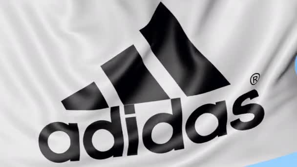 Primer plano de la bandera ondeante con inscripción y logotipo de Adidas, bucle sin costuras, fondo azul, animación editorial. 4K ProRes — Vídeos de Stock