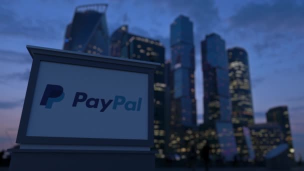 Placa de sinalização de rua com logotipo PayPal à noite. Desfocado arranha-céus distrito de negócios fundo. Editorial 3D renderização 4K — Vídeo de Stock