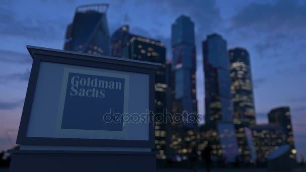 Placa de sinalização de rua com o logotipo do The Goldman Sachs Group, Inc. à noite. Desfocado arranha-céus distrito de negócios fundo. Editorial 3D renderização 4K — Vídeo de Stock