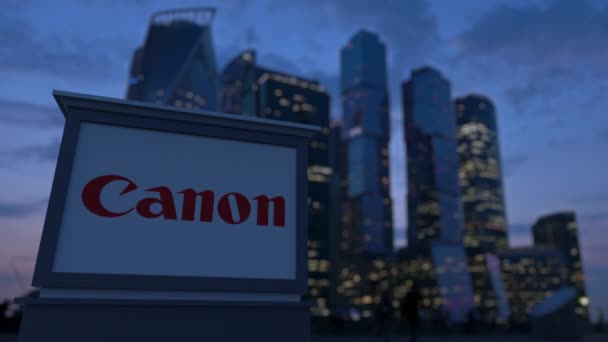 Gatan skyltar ombord med Canon Inc. logotyp på kvällen. Suddig business district skyskrapor bakgrund. Redaktionella 3d rendering 4k — Stockvideo