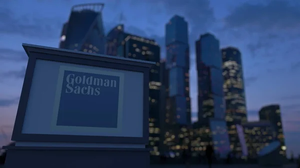 Уличная вывеска с логотипом The Goldman Sachs Group, Inc. вечером. Размытые данные о небоскребах в деловом районе. Редакционная 3D рендеринг — стоковое фото