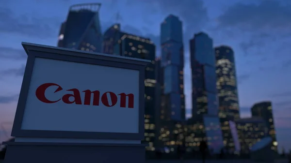 Straat signalisatie bord met Canon Inc.-logo in de avond. Zakelijke district wolkenkrabbers achtergrond wazig. Redactioneel 3D-rendering — Stockfoto