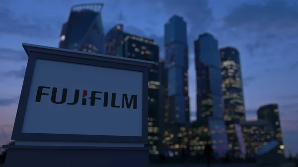 Gatan skyltar ombord med Fujifilm logotyp på kvällen. Suddig business district skyskrapor bakgrund. Redaktionella 3d-rendering — Stockfoto
