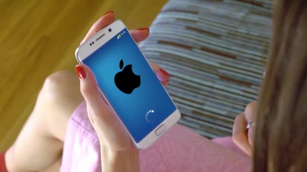 Giovane donna in possesso di un telefono cellulare con il caricamento di app mobile Apple. Clip editoriale concettuale 4K — Video Stock