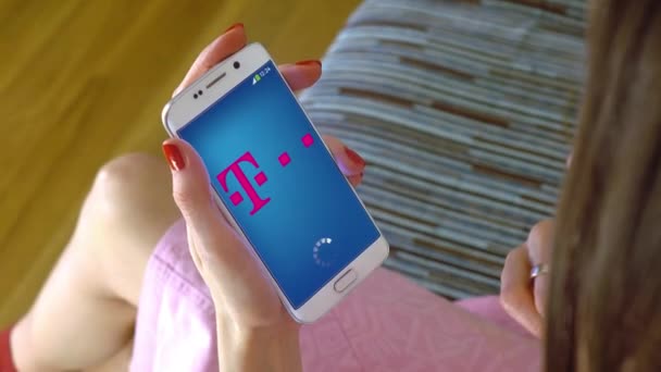 Молода жінка holding стільниковим телефоном із завантаженням T Telekom мобільних App. концептуальні редакційної 4 к кліп — стокове відео